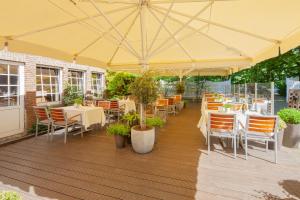 ein Restaurant mit Tischen und Stühlen unter einem gelben Sonnenschirm in der Unterkunft Hotel Bad Minden in Minden