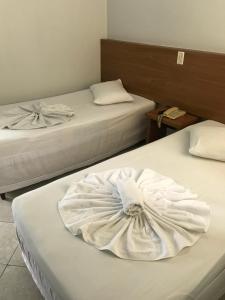 a hotel room with two beds with white towels on them at SM Palace Hotel in Divinópolis