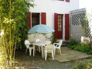 une terrasse avec une table, des chaises et un parasol dans l'établissement Appartement La Bananeraie, à Salies-de-Béarn