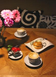 Tres tazas de café en una mesa de madera con flores en Penzion a relax centrum Andělka, en Hanušovice