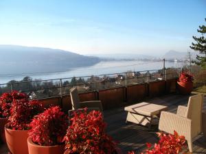 a balcony with red flowers and a table and chairs at Le Clos Du Lac - location de chambres in Veyrier-du-Lac