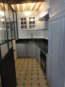 uma cozinha com armários brancos e piso em azulejo em La Maison des Augustines em Marselha