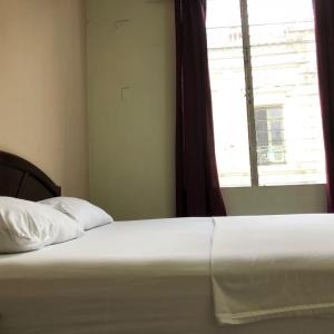 a bed in a bedroom with a window and a bedsheet at Hotel El Palacio in San Salvador
