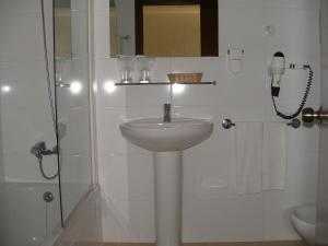 a white bathroom with a sink and a shower at Hotel Praia Dourada in Porto Santo