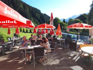 Un groupe de personnes assises à des tables sous des parasols dans l'établissement Gasthaus Vinaders, à Gries am Brenner