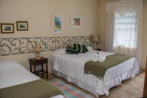 a bedroom with two beds and a window at Pousada Hospedaria da Villa in Tiradentes