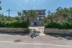 a building with a fence and trees in front of a street at Apartment PAULA in Trogir
