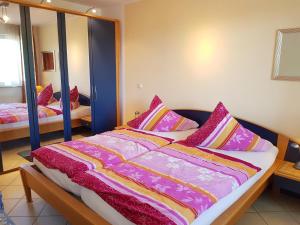 Schlafzimmer mit einem Bett mit rosa und lila Kissen in der Unterkunft Ferienwohnung mit Ostseeblick - 190m zum Strand in Ostseebad Karlshagen