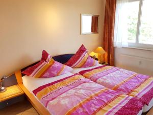 Bett mit bunter Bettwäsche und Kissen in einem Zimmer in der Unterkunft Ferienwohnung mit Ostseeblick - 190m zum Strand in Ostseebad Karlshagen
