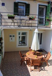eine Terrasse mit einem Tisch, Stühlen und einem Sonnenschirm in der Unterkunft Apartment Karega in Šibenik