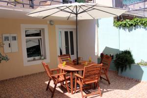 einen Holztisch mit Stühlen und einem Sonnenschirm auf einer Terrasse in der Unterkunft Apartment Karega in Šibenik
