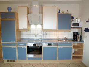 eine Küche mit blauen Schränken und einem Waschbecken in der Unterkunft Ferienwohnung mit Ostseeblick - 190m zum Strand in Ostseebad Karlshagen