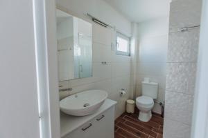 a white bathroom with a sink and a toilet at River View Boutique Apts in Ayia Napa