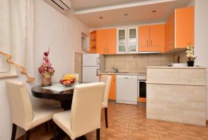 a kitchen with orange cabinets and a table and chairs at Apartment Markus in Makarska