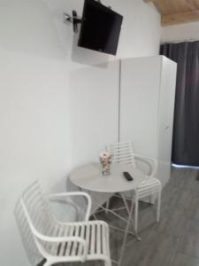 een kleine witte tafel met stoelen en een tv aan de muur bij La casetta di viale Paradiso in Pachino +22 foto's