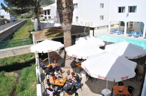 pessoas sentadas em mesas com guarda-sóis ao lado de uma piscina em Hotel Praia Dourada em Porto Santo