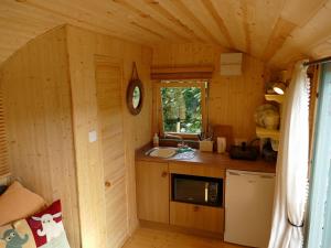 una pequeña cocina en una cabaña de madera con fregadero en The Lookout Shepherd's Hut, en Dolton