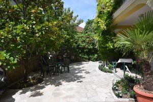 patio z krzesłami, stołami i drzewami w obiekcie Huter Apartments w mieście Herceg Novi