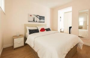 マドリードにあるCoqueto piso GOYA-WIZINK CENTERのベッドルーム1室(白いベッド1台、赤い帽子付)