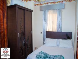 Schlafzimmer mit einem Bett mit einem Kopfteil aus Holz in der Unterkunft North Coast Princess Al Fayrouz in Marsa Matruh