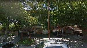 une voiture garée devant un immeuble arboré dans l'établissement Ruffus's Apple Cipolletti, à Cipolletti