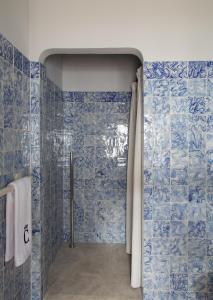 baño con paredes de azulejos azules y ducha. en Quinta da Côrte en Valença do Douro