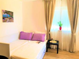 um quarto com uma cama com almofadas roxas e uma janela em Apartments Village em Lozovac