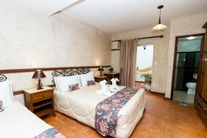 a hotel room with two beds and a window at Pousada Brasil Nativo in Cabo Frio