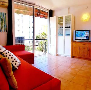 sala de estar con sofá rojo y TV en Apartamento Roymar Levante, en Benidorm