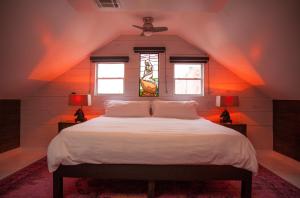 um quarto com uma grande cama branca e 2 janelas em Royal Street Inn & Bar em Nova Orleans