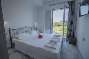 een slaapkamer met een wit bed en een groot raam bij Katsaros Luxury Apts 5min walk to beach in Tsilivi