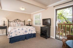 a bedroom with a bed and a television and a balcony at Ecola Creek Lodge in Cannon Beach