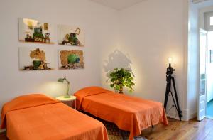 Zimmer mit 2 Betten mit orangefarbener Bettwäsche und einer Kamera in der Unterkunft Saldanha Apartment in Lissabon