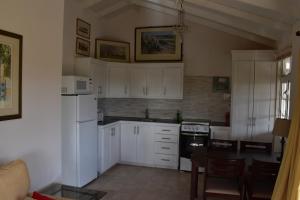 a kitchen with white cabinets and a table in it at The Pool House in Saint Philip