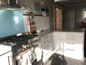a kitchen with a stove and white cabinets at Fossil Coast B&B in Hawera