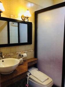 y baño con lavabo, aseo y espejo. en Playa Tropical Resort Hotel, en Currimao