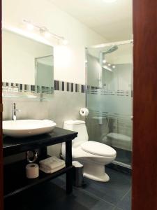 a bathroom with a toilet, sink, and mirror at Illa Hotel in Cusco