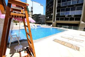 una gran piscina con sillas y sombrilla en Apartamento Leblon - Rio Design, en Río de Janeiro