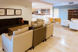 a waiting room with couches and a table and chairs at Minura Cala Galdana & Apartamentos d'Aljandar in Cala Galdana