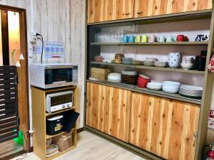 a kitchen with a microwave and plates on shelves at Guesthouse Honobono in Fujikawaguchiko