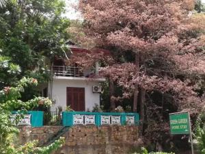 ein Haus mit rosa blühenden Bäumen davor in der Unterkunft Green Garden Homestay in Giritale