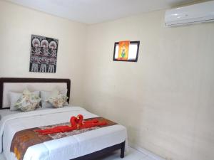 a bedroom with a bed with a red ribbon on it at Twins Homestay in Canggu