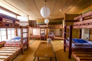 Pokój z kilkoma łóżkami piętrowymi i stołem w obiekcie Guesthouse Honobono w mieście Fujikawaguchiko