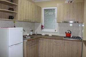 a kitchen with wooden cabinets and a white refrigerator at Easy Guest House in Tbilisi City