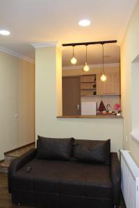 a black couch in a living room with a kitchen at Easy Guest House in Tbilisi City