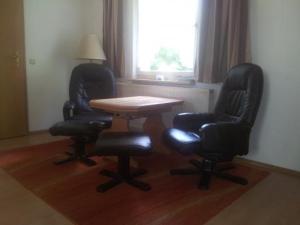ボルンにあるFeWo1の窓のある客室で、椅子2脚とテーブル1台が備わります。