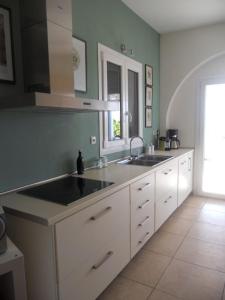 a kitchen with white cabinets and a sink and a window at Villa Kampos Paros in Pounda