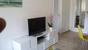 una sala de estar con TV en un centro de entretenimiento blanco en Jardins du Pont du Lys, en Juan-les-Pins