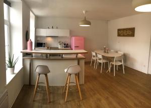eine Küche mit einem Tisch und einem rosa Kühlschrank in der Unterkunft Le Wim'Heureux in Wimereux