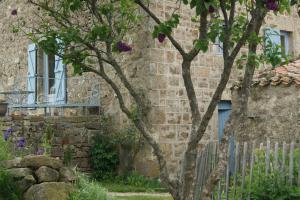 a brick building with a fence and a tree at cool la source in Burdignes